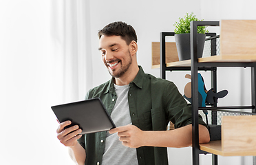 Image showing happy smiling man with tablet pc at shelf at home