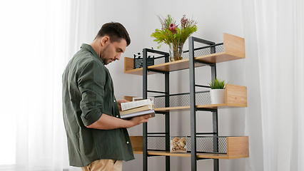Image showing man with books decorating home and arranging shelf