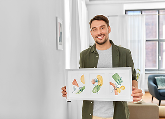 Image showing smiling man decorating home with picture in frame