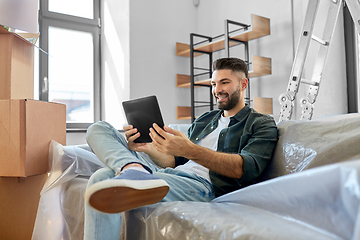 Image showing man with tablet pc and boxes moving into new home