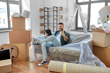 Image showing man with tablet pc and boxes moving into new home