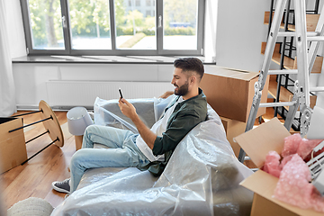 Image showing man with smartphone and boxes moving into new home