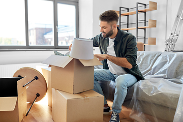 Image showing happy man unpacking boxes and moving to new home