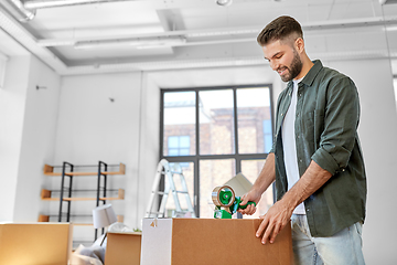 Image showing man with adhesive tape packing box at new home