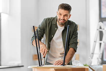 Image showing happy man assembling coffee table at new home