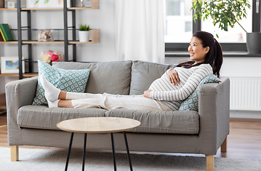 Image showing happy pregnant asian woman sitting on sofa at home