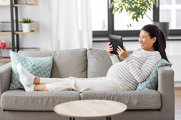 Image showing happy pregnant asian woman with tablet pc at home