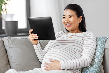 Image showing happy pregnant asian woman with tablet pc at home