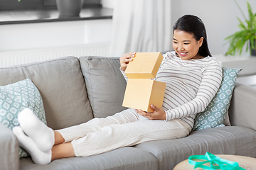 Image showing happy pregnant woman opening gift box at home