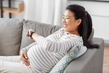 Image showing happy pregnant woman with smart watch at home