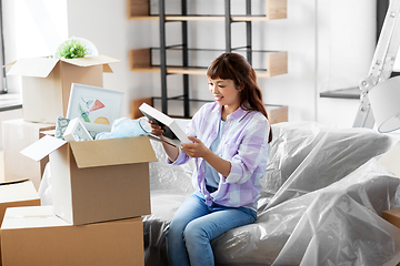 Image showing happy woman unpacking boxes and moving to new home