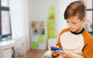 Image showing boy with smartphone texting or playing at home