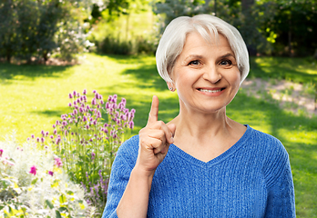 Image showing smiling senior woman pointing finger up