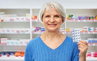 Image showing smiling senior woman with pack of pills