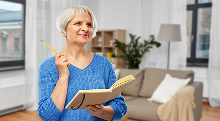 Image showing senior woman with pencil and diary or notebook