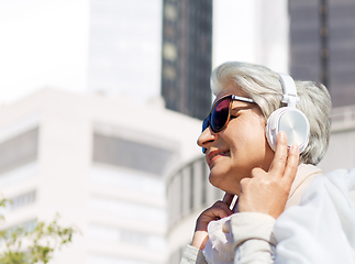 Image showing old woman in headphones listens to music in city