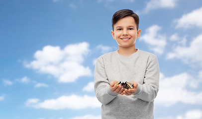 Image showing smiling boy holding pile of alkaline batteries