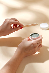 Image showing hands holding jar of blue cosmetic clay mask