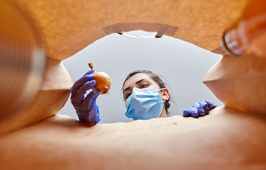 Image showing woman in gloves and mask with food in paper bag