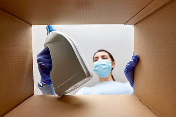 Image showing woman in mask taking cleaning supplies from box