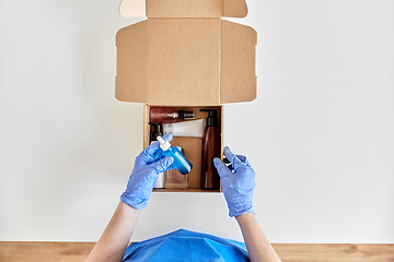 Image showing hands in gloves packing parcel box with cosmetics