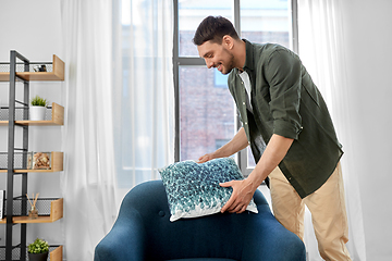 Image showing happy smiling man arranging chair cushion at home