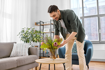 Image showing man placing flowers on coffee table at home