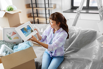 Image showing happy woman unpacking boxes and moving to new home