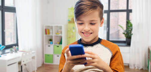 Image showing boy with smartphone texting or playing at home