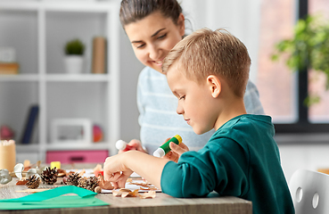 Image showing mother and son making pictures of autumn leaves