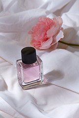 Image showing bottle of perfume and flower on white sheet