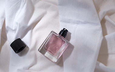 Image showing bottle of perfume and cap on white sheet