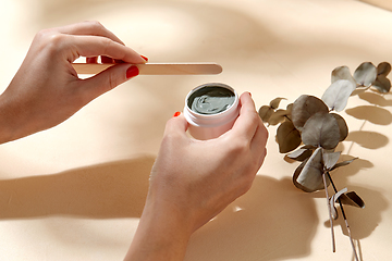 Image showing hands holding jar of blue cosmetic clay mask