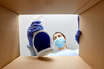 Image showing woman in mask taking cleaning supplies from box