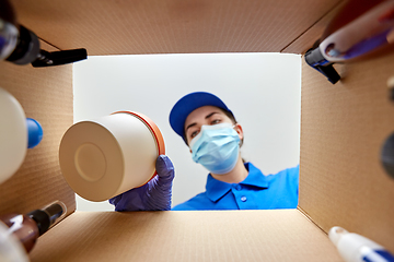 Image showing woman in mask packing parcel box with cosmetics