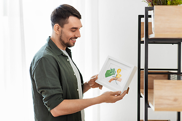 Image showing man decorating home with picture in frame