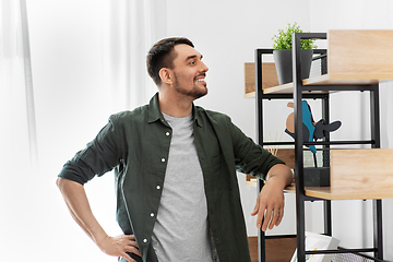 Image showing happy smiling man standing at shelf at home