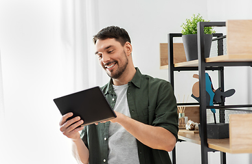 Image showing happy smiling man with tablet pc at shelf at home