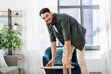 Image showing man placing coffee table next to sofa at home