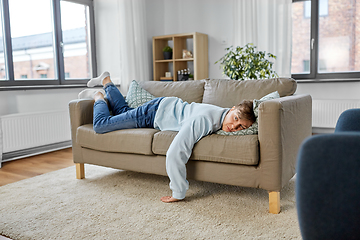 Image showing bored or lazy young man lying on sofa at home