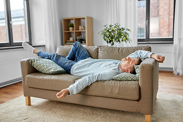 Image showing bored or lazy young man lying on sofa at home