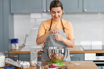 Image showing happy young woman cooking food on kitchen at home