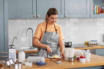 Image showing happy young woman cooking food on kitchen at home