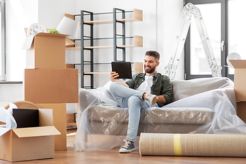 Image showing man with tablet pc and boxes moving into new home