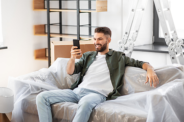 Image showing man with smartphone and boxes moving into new home