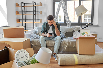 Image showing sad man with smartphone and boxes moving home