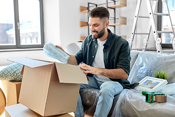 Image showing happy man unpacking boxes and moving to new home