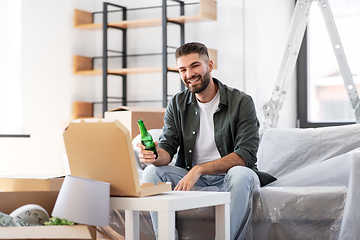 Image showing man with box of pizza and beer bottle at new home