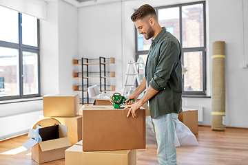 Image showing man with adhesive tape packing box at new home