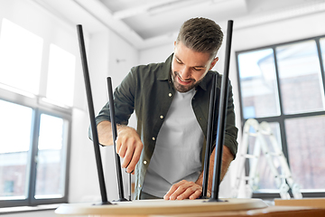 Image showing happy man assembling coffee table at new home